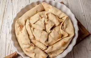 Arrange the prepared rolls in a round shape with a diameter of 22-24 cm (lubricated with vegetable oil), folding them with snails.