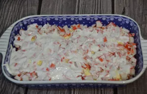 The fourth layer is finely chopped crab sticks, on top - a layer of mayonnaise.