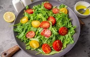 Cut the cherry tomatoes in half and lay out on the leaves of the rukola.
