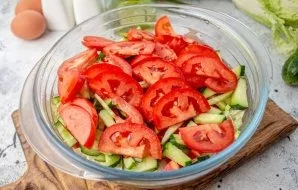 Cut the tomatoes into thin slices and put in a salad bowl.