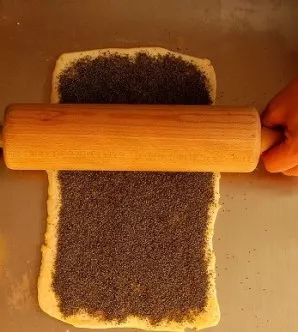 Put the filling and iron it with a spoon. Lightly squeeze poppy seeds into the dough with a rolling pin to make the roll denser and smoot...