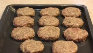 With wet hands, form small round balls from the minced meat and press them on both sides, place them on a baking sheet greased with veget...