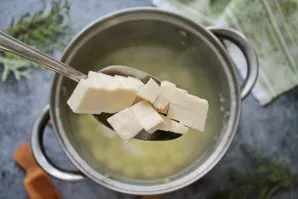 Cut the processed cheese into small cubes and put in a saucepan with potatoes. Cook the soup until the cheese is completely melted, stirr...
