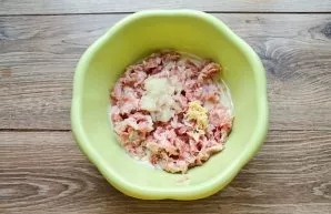 Peel and grate the onion and garlic on a fine grater, put them in a bowl with the dough and minced meat.