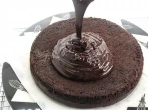 Cool the cake and put it on a large plate. We put the chocolate in a saucepan, pour the cream, put it on the fire and stir until steam co...