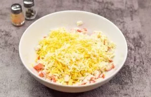 Peel the boiled eggs and grate on a fine grater, put in crab sticks. Also grate the processed cheese on a fine grater and add to all the ...