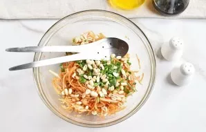 Add peanuts and chopped onion leaves to the salad. Squeeze the garlic. Stir again.