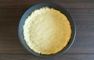 Take a 26 cm baking dish, line it with baking paper. Pour the dough into the mold. Distribute it along the bottom, forming high sides. Pi...