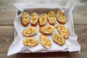 Line the baking sheet with baking paper and lay out the prepared pieces of baguette. Add the filling inside and press it.