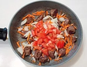 Wash the tomatoes, dry them and cut them into medium-sized cubes. Add to the pan with the meat and vegetables.