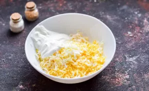 Grate the melted cheese on a fine grater, put a boiled egg grated on a fine grater. Add sour cream, salt, pepper, garlic. Mix everything.