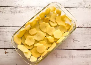 Wash the potatoes, peel them, cut them into thin slices and put them in a baking dish greased with vegetable oil.