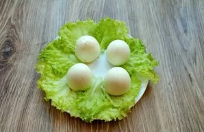 Wash the lettuce leaves, dry them and place them on plates. Place the eggs cut side down on the leaves.