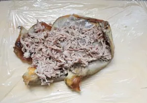 Spread the cling film and place the cooked ears on it. Place the meat and garlic in an even layer on top.