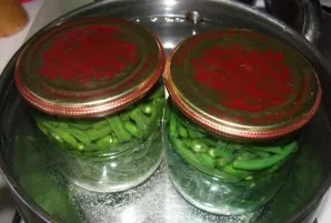 Fill the jars with marinade. Close them with lids. Place the jars with beans to sterilize for 15 minutes.