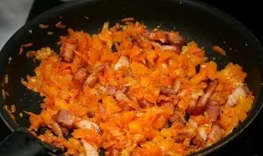 Then add grated carrots to the meat and season the contents of the pan with tomato paste. Mix well again and continue to simmer.