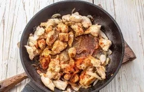 While the chicken is slightly pale, add spices: suneli hops, sweet paprika, ground black pepper. Bake for 1 minute.