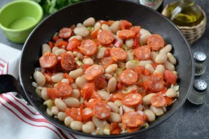 Peel the chorizo sausages, cut into thin circles, put in a pan, simmer for another 5 minutes.