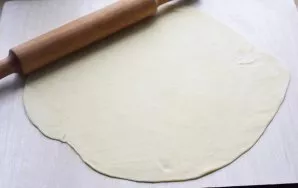 Sprinkle the work surface with flour. Roll out half of the dough in a thin layer.