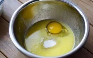 Pour the butter (80 grams) melted in a saucepan over low heat into a separate bowl, add white sugar, vanillin, beat the egg.