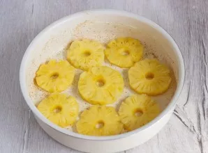 Grease the form with butter, sprinkle with breadcrumbs and put canned pineapple on the bottom.