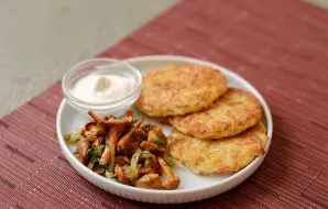 Put fried chanterelles and potato pancakes on a plate.
