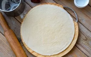 Then divide all the dough into two equal parts. Roll out one part of the dough thinly using a rolling pin (for me, the diameter is 26 cm).