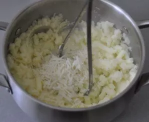 Drain the water from the boiled potatoes, crush the mashed potatoes, add 2 tablespoons of Parmesan