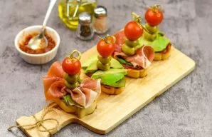 On each sandwich, roll a skewer of olive and cherry tomatoes.