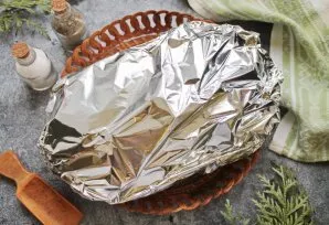 Cover the tin with baking foil and place in a hot oven. Bake the meat at a temperature of 180 degrees for an hour.