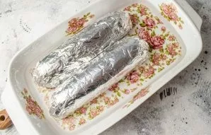 Wrap the sausages in the film tightly in foil. Put them in a suitable baking dish, pour water to cover to half. Put the form with sausage...