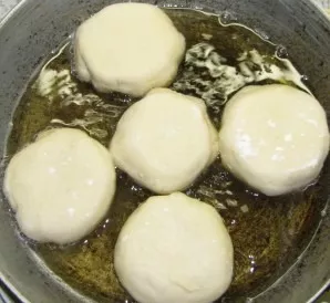 We start baking beliash. Pour oil into a deep frying pan, first fry with the holes turned down.