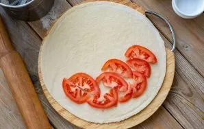 Wash the tomatoes, dry with a kitchen towel and cut into thin semicircles. Put a few pieces of tomatoes on half of the rolled dough.