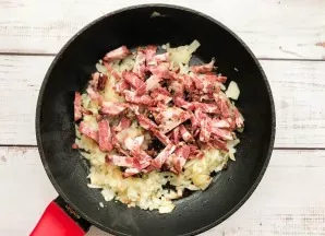 In a well-heated pan with vegetable oil, fry finely chopped onion and brisket.
