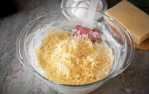 Grate the cheese on a coarse grater. Put half in a bowl with a curd mixture.