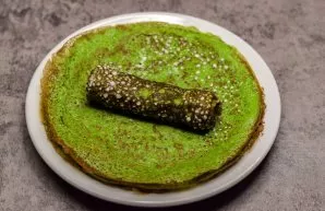 Roll the pancakes into rolls. Spinach pancakes with salmon are ready.