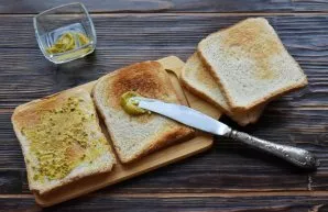 On toasted slices of bread, apply French mustard in a thin layer.