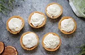 Beat the cream with icing sugar into a fluffy mass. Put the cream in a bag with an asterisk and squeeze on the fruit. Garnish the tartlet...
