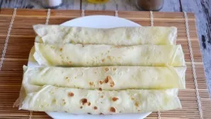 Roll the pancake into a dense roll. When serving, cut into small pieces and decorate with salmon.