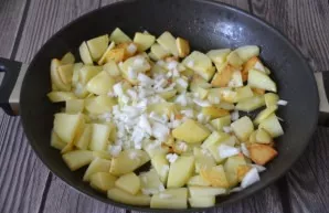 After the potatoes have been fried on one side, stir, salt, add the second half of the onion, fry for another 10 minutes