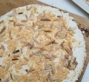 Spread the bottom layer of biscuit with a fourth part of the cream, add chopped almonds and chopped wafers.