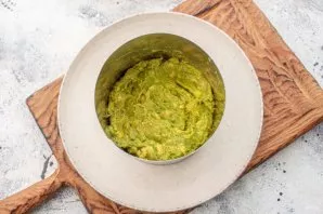 Put a serving ring on the container. Spread the first layer with avocado puree.