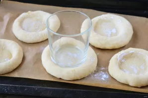 Dip the bottom of the glass in flour, then press the dough balls with the bottom and form a cheesecake with a recess for the filling.