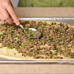 Sprinkle the dough with a little starch. This will prevent the filling from wetting the dough. Spread 1/2 of the mince evenly.