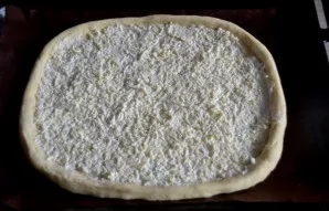 Transfer the dough to a baking tray and spread the mozzarella and sour cream sauce on top.